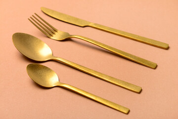 Clean golden cutlery on beige background