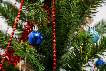 Blue Christmas ornament and red beads on tree