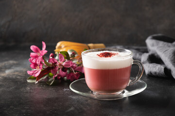 Pink matcha latte with powder decorated sakura flowers on dark black background. Trendy beverage....