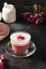 Pink matcha latte with powder decorated sakura flowers on dark black background. Alternative vegan trendy beverage. Caffeine free. Vertical