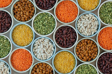 Pattern of various types of beans and lenties  in multi-colored round ceramic bowls on a brown...