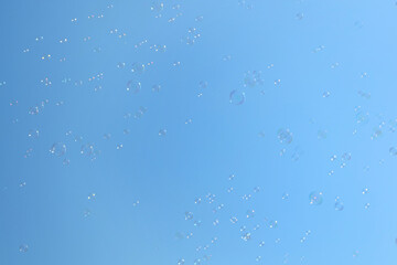 Beautiful soap bubbles floating on blue sky background