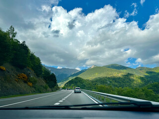 A car driving on a highway through a scenic mountain landscape.
