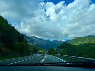 A car driving on a highway through a scenic mountain landscape.