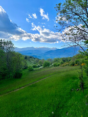 Scenic view of rolling hills, mountains, and a cloudy sky under sunlight. Mountain range with wildflowers. Landscape with Rolling Hills and Cloudy 