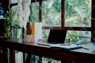 Modern minimalist workspace with laptop, document folders, and rubber stamp on wooden table beside...