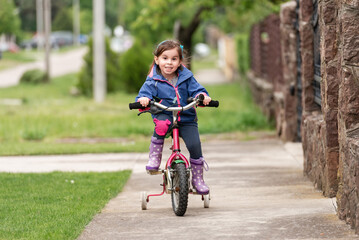 Happy child riding bicycle on sidewalk in suburban neighborhood