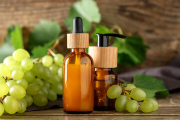 Bottles of cosmetic grape seed oil on wooden background