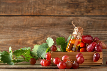 Bottle of cosmetic grape seed oil on wooden background