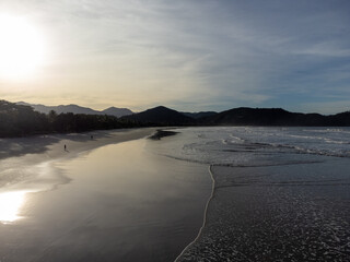 beautiful reddish sunrise on the beach with small waves and mountain horizon