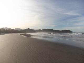 Person alone on distant horizon of long beach at beautiful sunrise