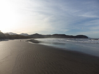 Person alone on distant horizon of long beach at beautiful sunrise