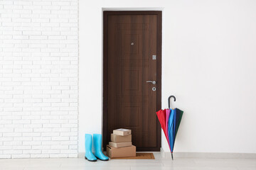 Interior of modern hallway with door mat, parcels, gumboots and umbrella