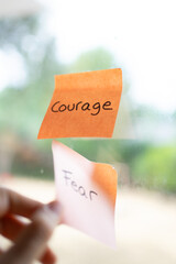 Hand removing fear sticky note choosing courage