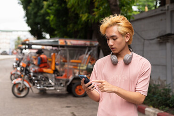 Young man tourist in Thailand ordering taxi with mobile phone