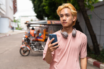 Young man tourist in Thailand ordering taxi with mobile phone