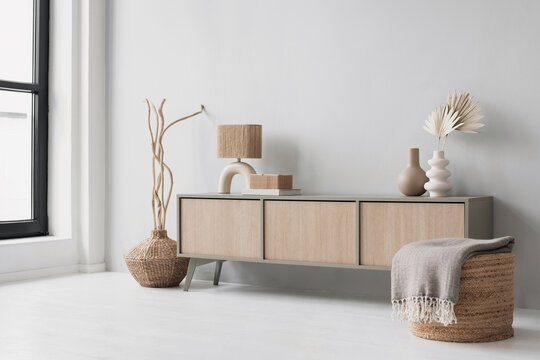 Fototapeta Modern scandinavian style interior with chair, commode and trendy lamp. Elegant living room decor. Home staging and minimal interior design concept. Empty wall copy space.