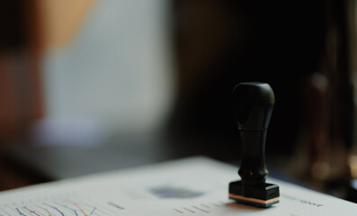Close-up of a summary report stamped 'APPROVED' with a black rubber stamp on an office desk. Pen,...