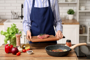 Woman cooking tasty steak in kitchen