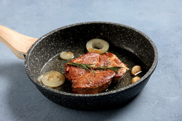 Frying pan with roasted steak on blue background