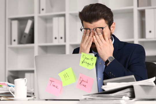 Stressed businessman with a lot of work trying to meet deadline in office