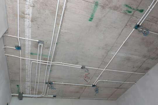 Electrical conduit system installation on exposed concrete ceiling of residential building