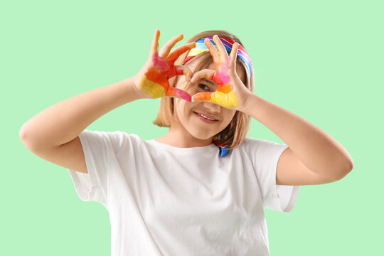 Teenage girl making heart with her painted hands on turquoise background