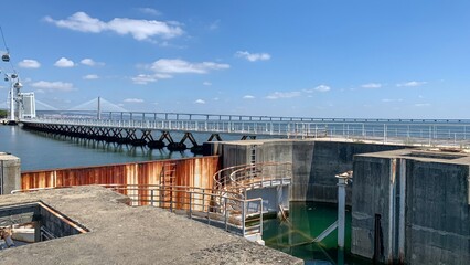 Concrete and rust embrace over azure waters, echoing industrial whispers during Portugal's Lumiar...
