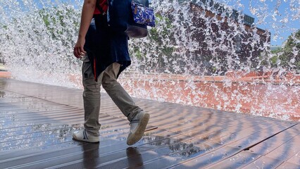 Youthful wanderer with a backpack strolls past splashing urban fountain, embodying International Water Day wanderlust, vibrant urban mood May 23, 2025, Lisbon, Portugal