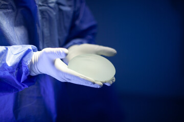 Surgeon doctor holding silicone breast implant in clinic