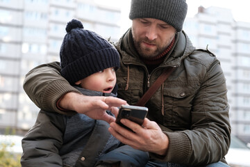 Father and son walking down on sidewalk together. Portrait of a handsome middle-aged man with...