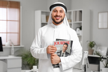 Arab businessman with magazines in office