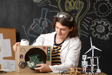 Male inventor making device at table in workshop