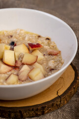 pieces of peach in oatmeal, quickly cooked oatmeal porridge with dried fruits and berries and pieces of fresh peach, closeup