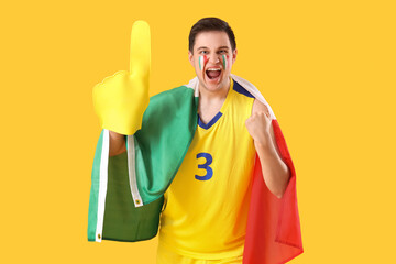 Male sports fan with Italian flag and foam hand on yellow background