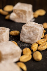 Turkish delight in powdered sugar with nuts inside, oriental sweets Turkish delight with peanuts on a slate board, side view