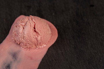 melting pink ice cream on a black slate, sweet cold pink ice cream with strawberry flavor