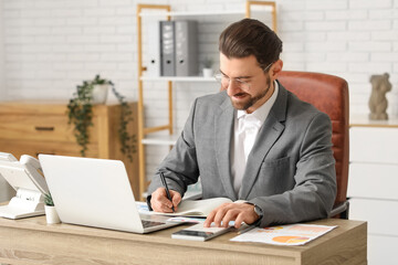 Fototapeta premium Businessman working with calculator at table in office