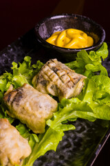 Involtini di melanzane su un letto di insalata e accompagnati con della senape serviti come antipasto in una braceria 