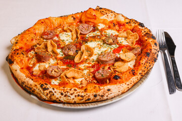 Pizza tradizionale napoletana con sugo di pomodoro, salsiccia, mozzarella e fagioli servita in una pizzeria elegante