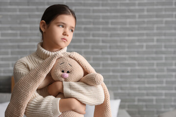 Sad girl with toy bunny at home. Adoption concept