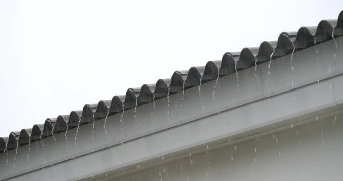 Raining on the Roof: Raindrops cascade from a roof, creating a tranquil and atmospheric scene, against the backdrop of a grey sky. Capturing the essence of a rainy day.