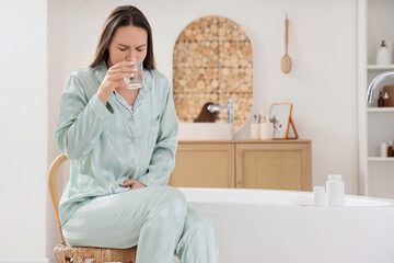 Young woman on period taking antispasmodic drugs in bathroom