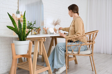 Young woman with cosmetic products on table in dressing room