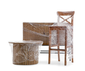 Chest of drawers with chair and table wrapped in stretch film on white background