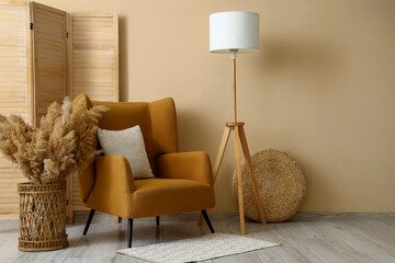 Interior of stylish living room with brown armchair, standard lamp and pampas grass