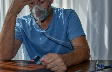 Oxygen face mask is placed on a man with breathing difficulty due to his lung disease. Covid-19,...