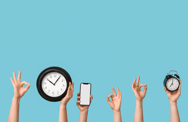 Obraz premium Female hands with clocks and blank mobile phone showing OK on blue background