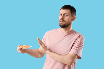 Young man rejecting shrimps on blue background. Food Allergy Awareness Month