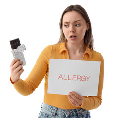 Young woman holding paper with word ALLERGY and chocolate bar on white background